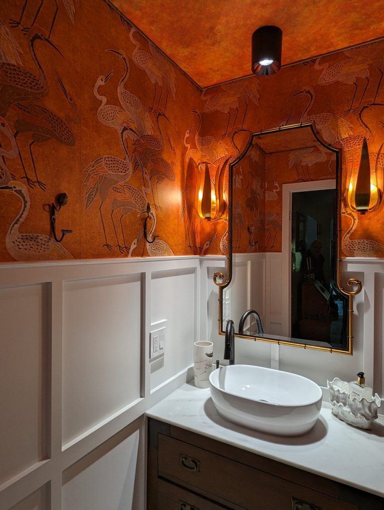 bathroom with orange and white walls, dark lighting, white sink and countertop